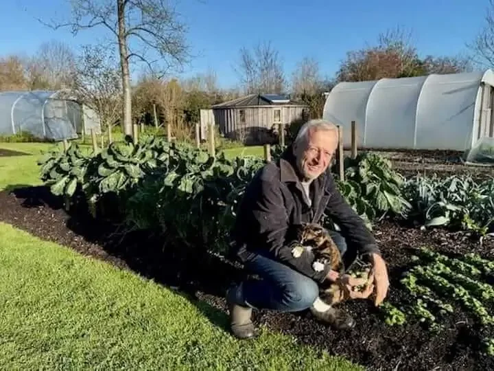 Charles Dowding in No Dig garden in front of poly tunnel.
