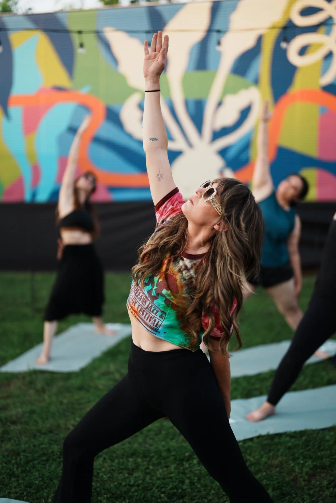 A group of women doing yoga with goats in a garden.