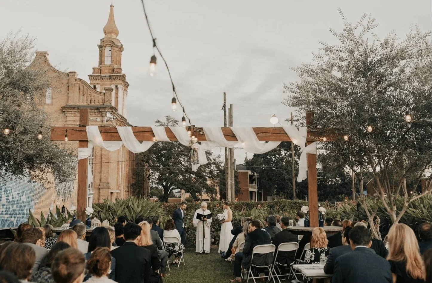 Wedding ceremony outside in garden venue with guests sitting down.