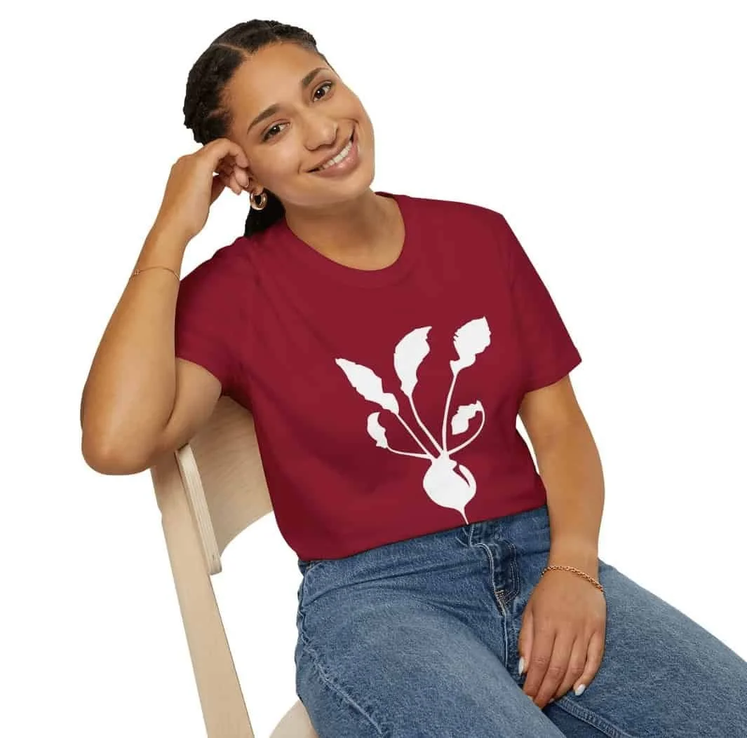 Brown skin woman wearing red Paradigm Gardens shirt with white radish logo.