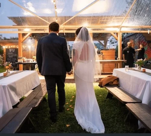 married couple holding hands under beautiful clear tent at New Orleans garden venue.