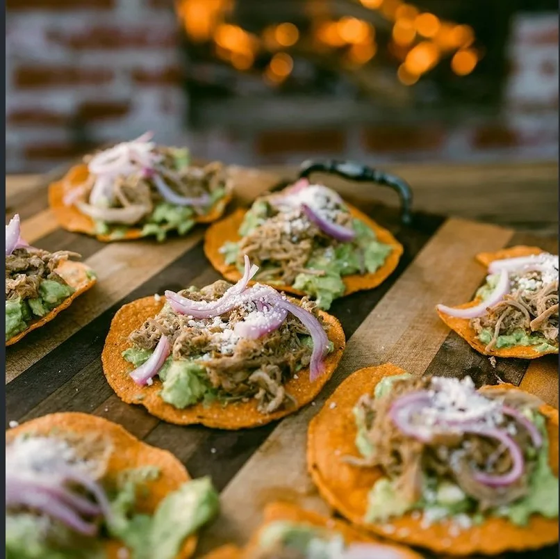 Farm-to-table pulled pork and guacamole tostada with pickled onion and cotija cheese.