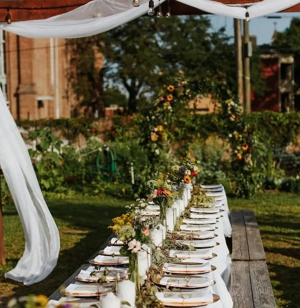 Fully set table with linen, flatware, and floral decorations in beautiful garden setting.
