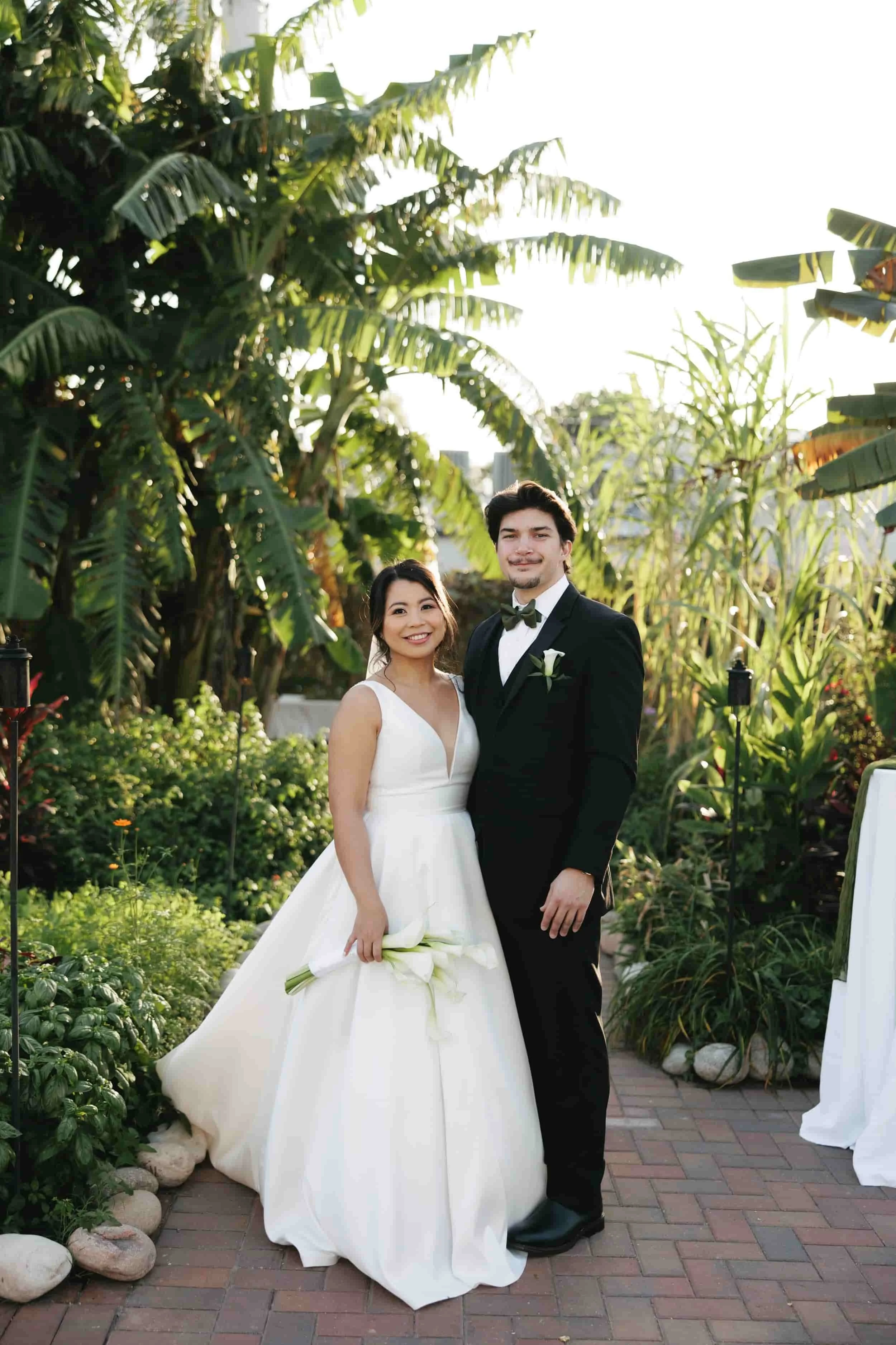Newly wed couple smiling with banana trees behind in New Orleans garden wedding venue