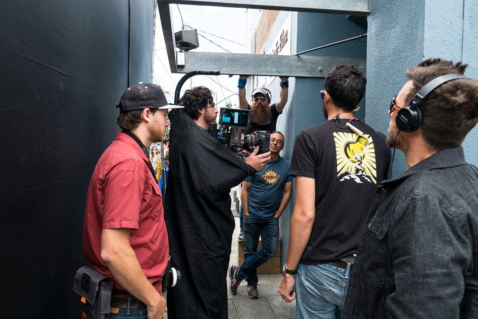 DP Matt Mayotte holding the camera, with Gaffer Cyrus leaning on the wall, and Boom operator David behind him.