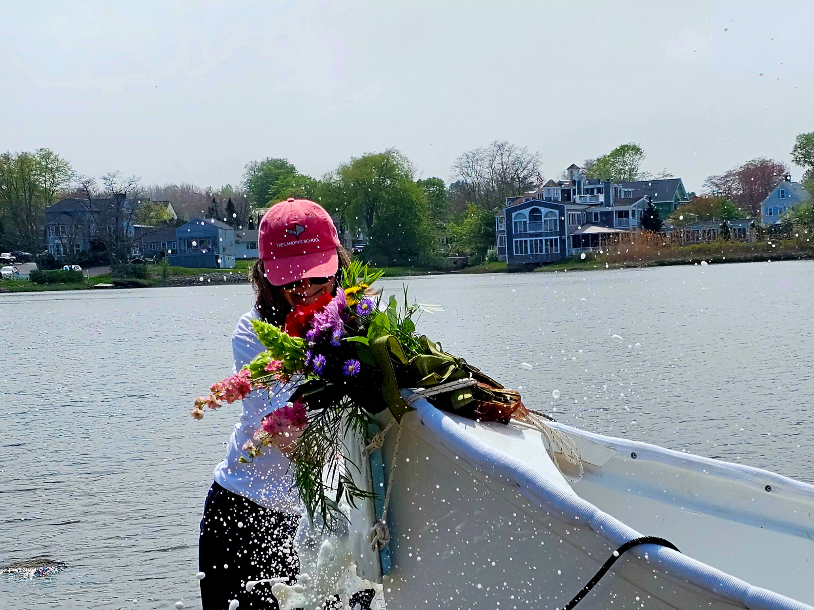 Laurie Hurley smashing a ceremonial bottle of champagne on a student-built boat