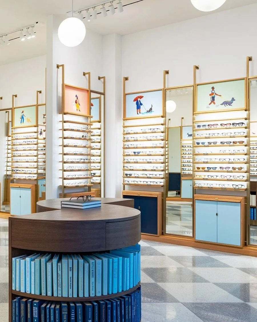 Eyeglasses display in a modern optical store with colorful wall art illustrations of people walking dogs by illustrator Lucy Engelman.