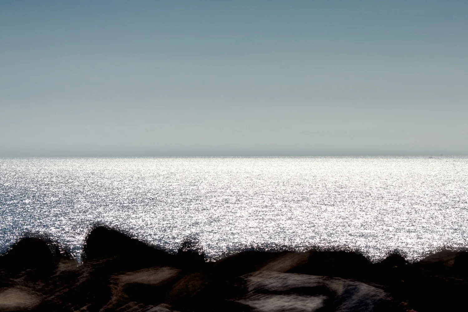 Seascape with foreground rocks.