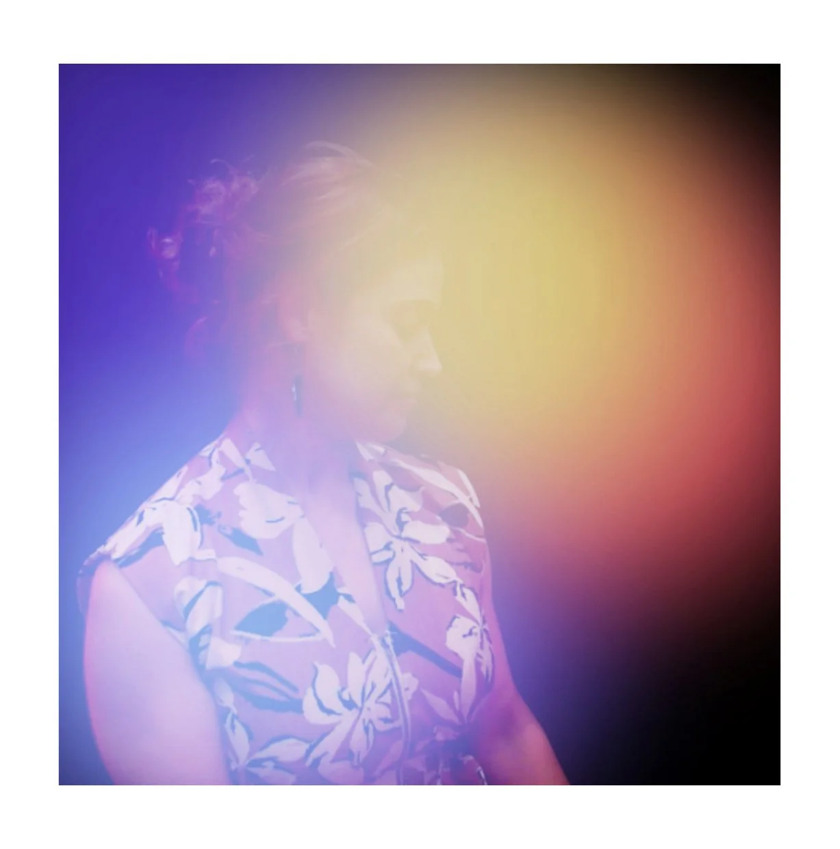 Side profile of a woman with short, styled hair, wearing a floral patterned sleeveless top, with a colorful rainbow gradient overlay.