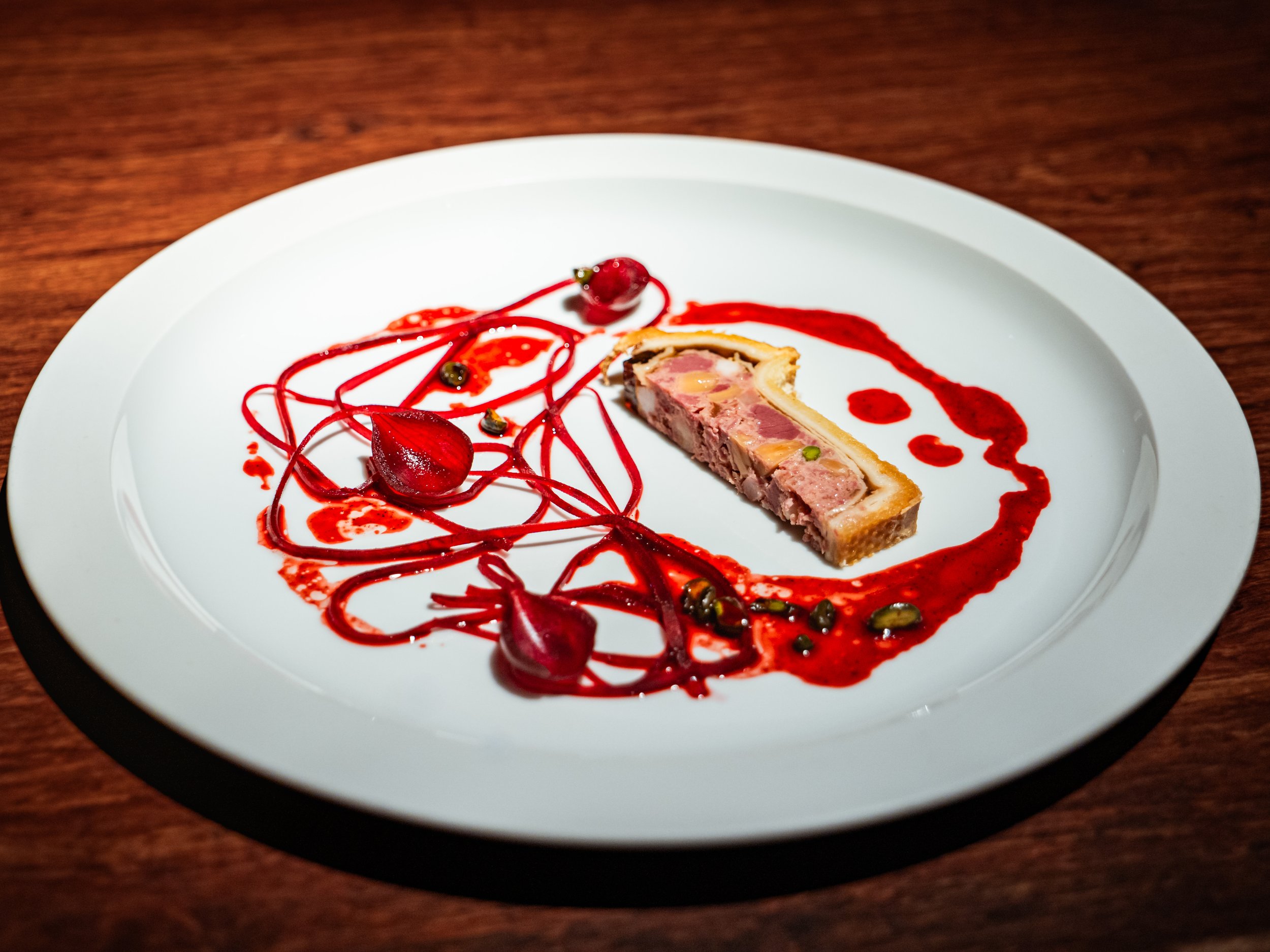 Pastete vom Rind auf weißem Teller auf Holzuntergrund.