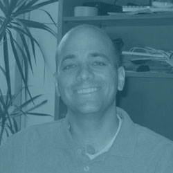 Corporate head shot of a man seated in a university office.