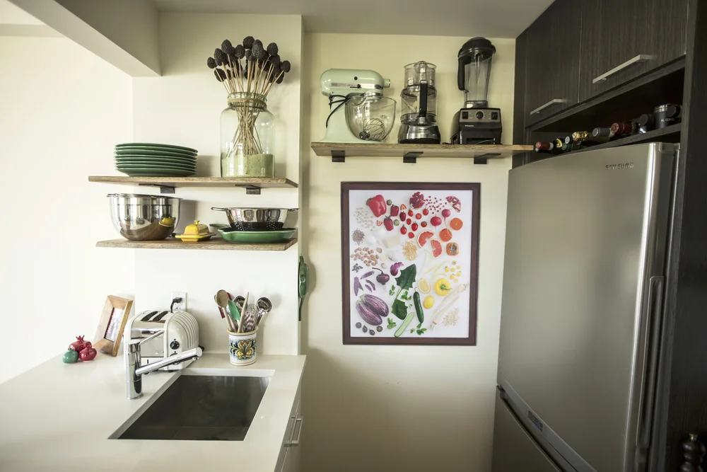Holly's "Colors of the Market" photographic print is both on a small wall and near a kitchen sink. 