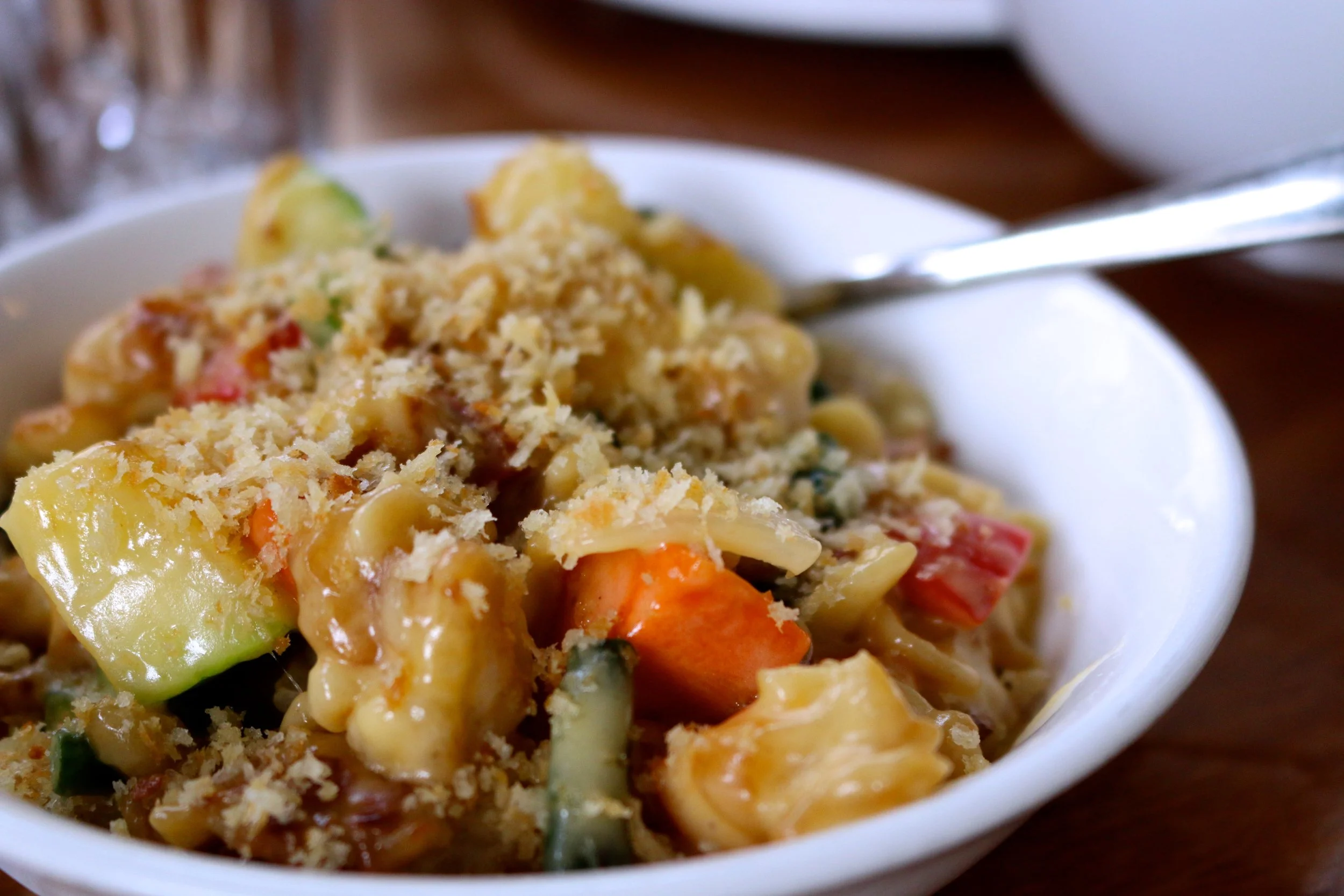 SPATZLE MAC N CHEESE - HOUSEMADE EGG NOODLES, MARKET VEG, WHITE WINE, AND CHEDDAR JACK.