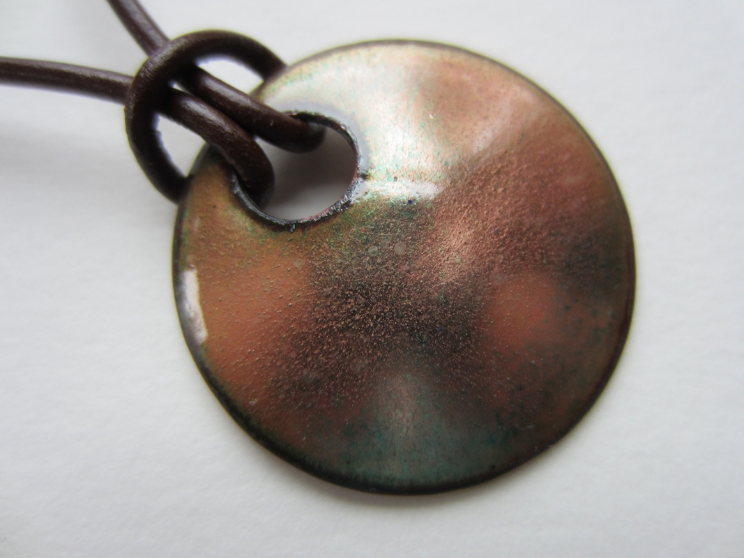 Copper with enamel, warm orange, pink, and green. 1 1/4 inch diameter