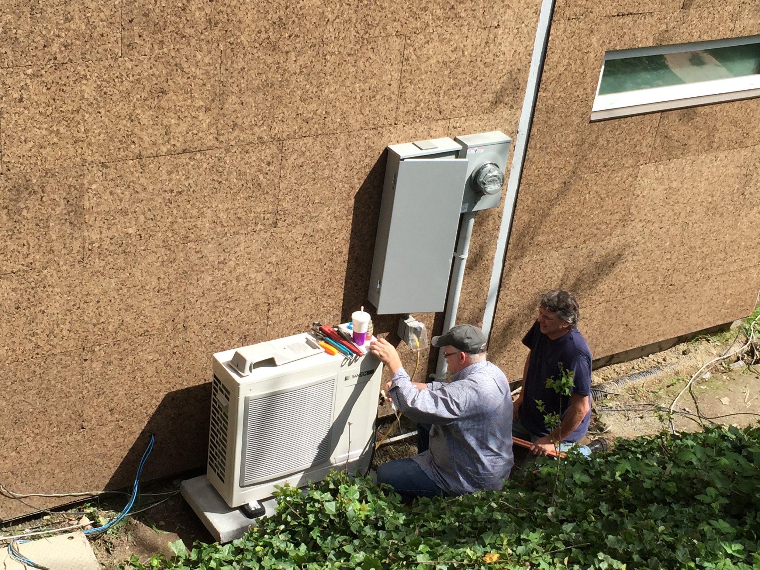Mark Jerome with WSU Energy extension  works on the exterior heat pump and the home's service panel