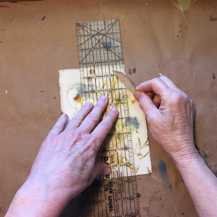Tearing the paper to fit on the board artist Carol Ann Webster
