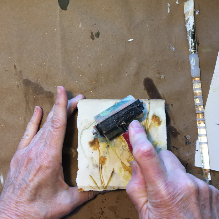 Use a brayer to press down paper on board artist Carol Ann Webster