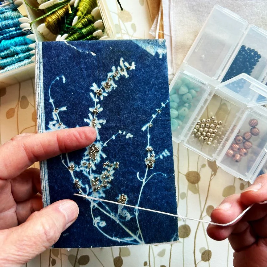 Hands stitching on a tea bag with beads