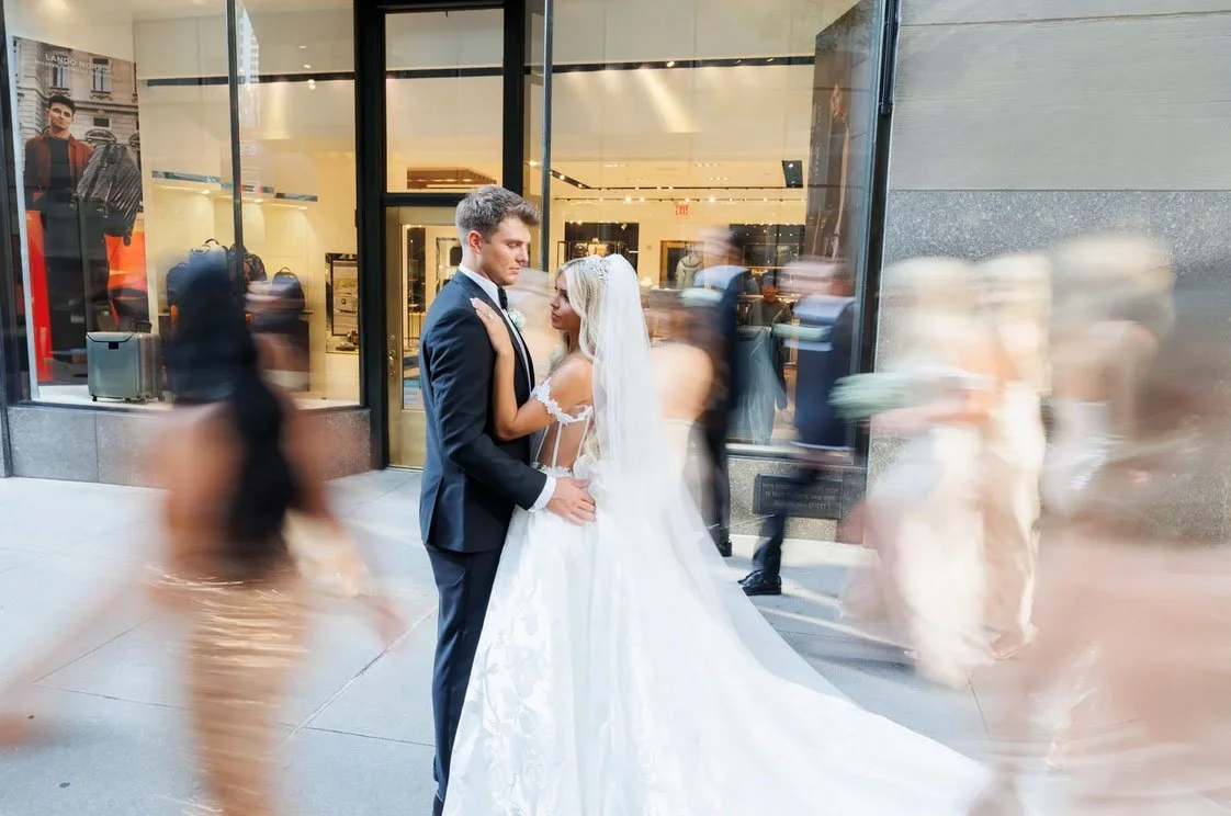 Zach Wilson and his wife sharing a moment as the bridal party is walking by blurry in NYC 