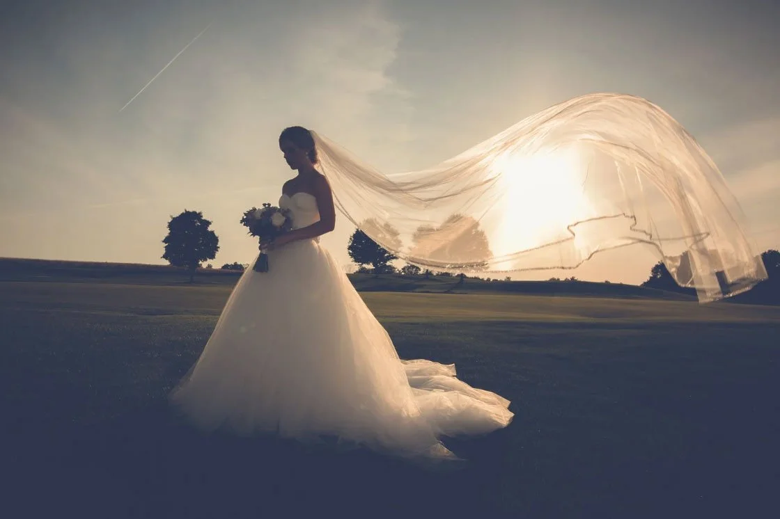 A bride's veil is flowing in the wind at Trump National Bedminster, NJ on her wedding day. Stand-alone wedding portrait. 