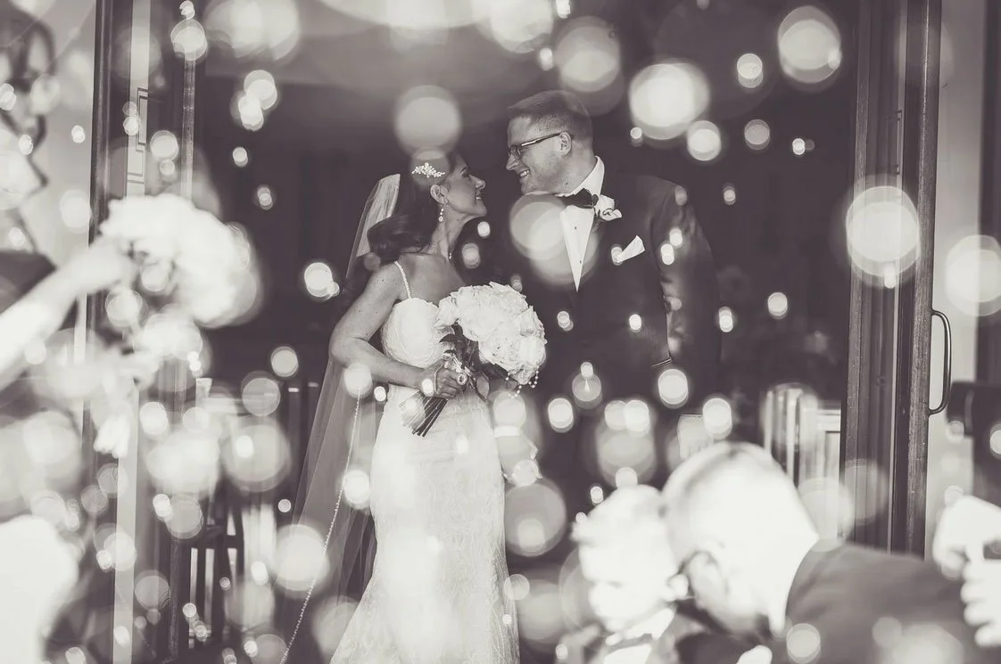 Bride & groom are looking at each other as they exit their ceremony. Guests are blowing bubbles and cheering. Wedding venue was Valley Regency in Clifton, NJ