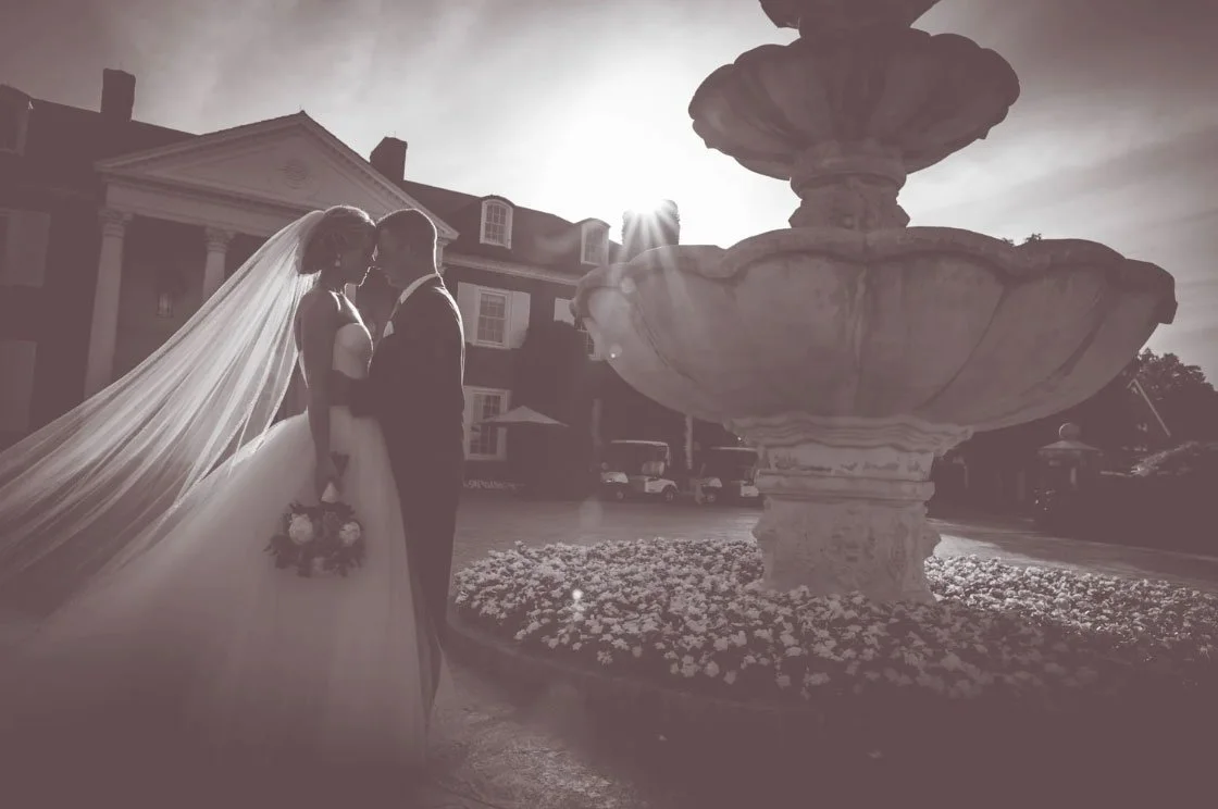 Dark & Moody wedding photo with a black and white filter of a bride & groom touching foreheads out front of the Trump National Bedminster venue. 