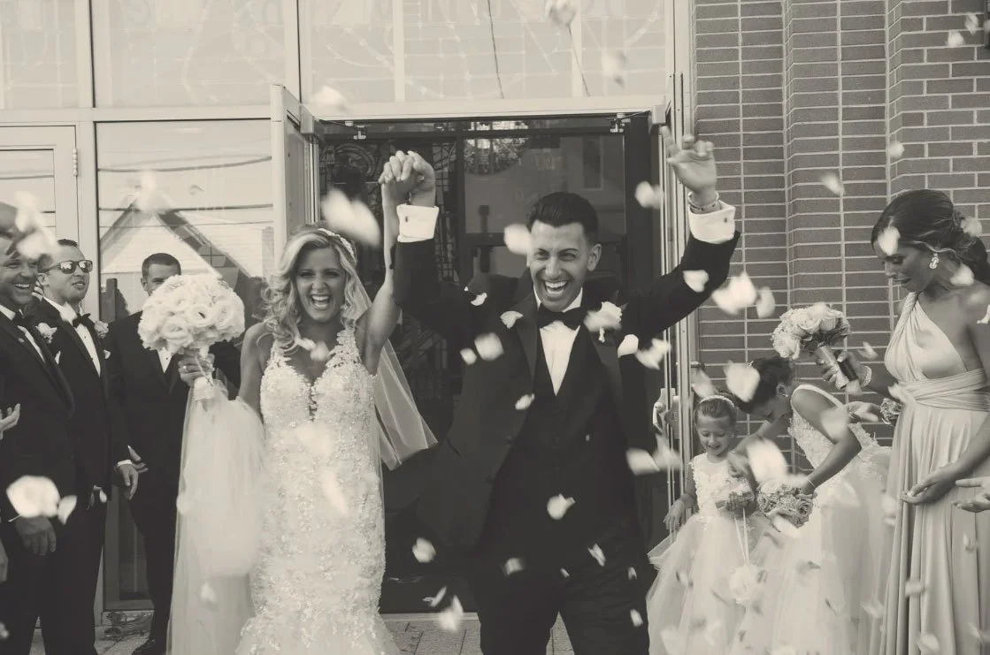 Photojournalistic Candid NJ Wedding Photographer captured a Bride & groom leaving church ceremony with flowers being tossed. 