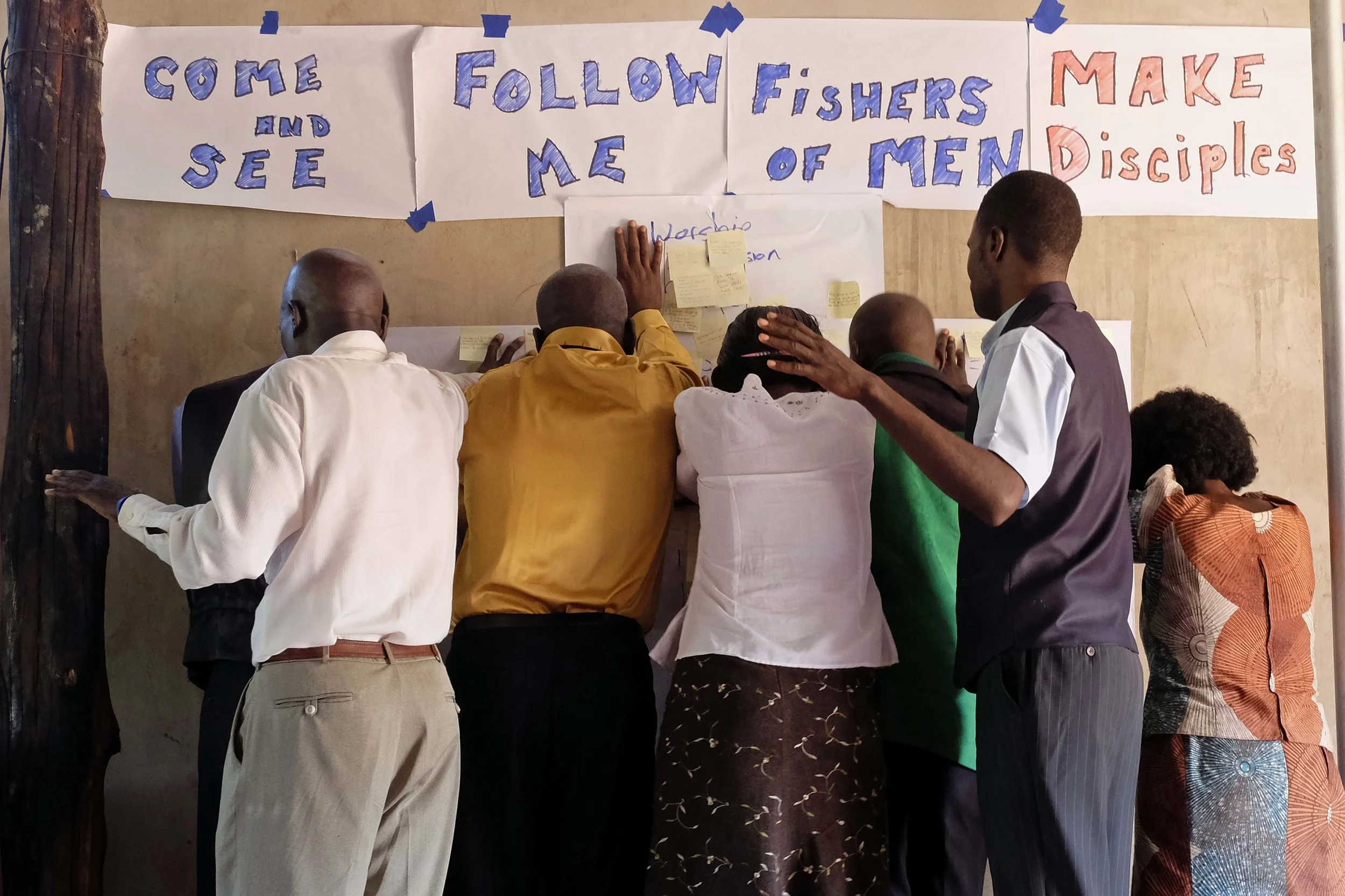 Students pray during closing worship over prayer requests posted on the discipleship cross.
