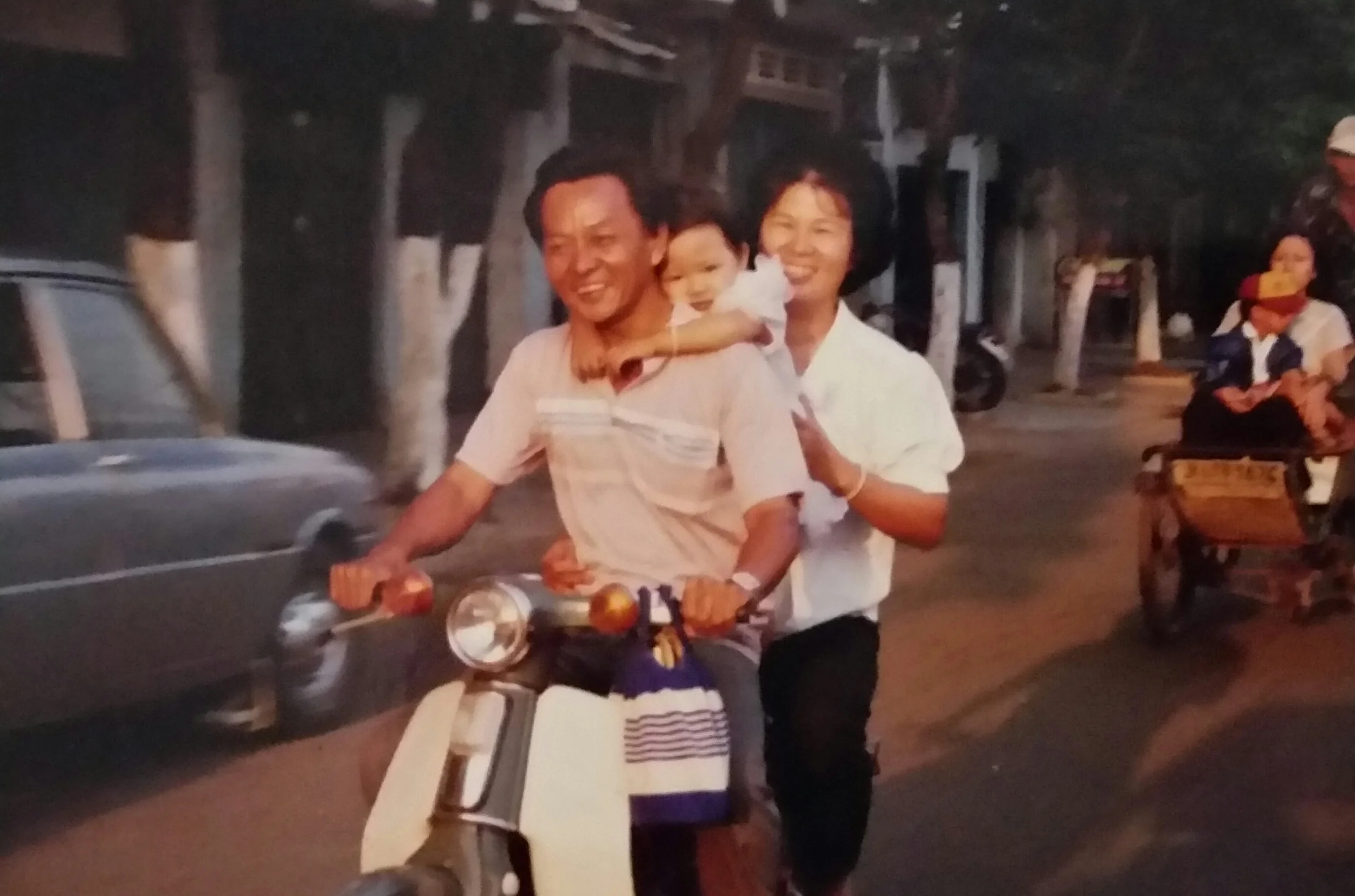 My parents and me on the road, riding extremely safely on our family scooter.