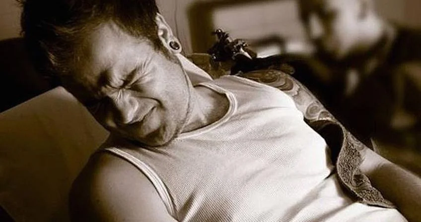 man in pain tattoo session