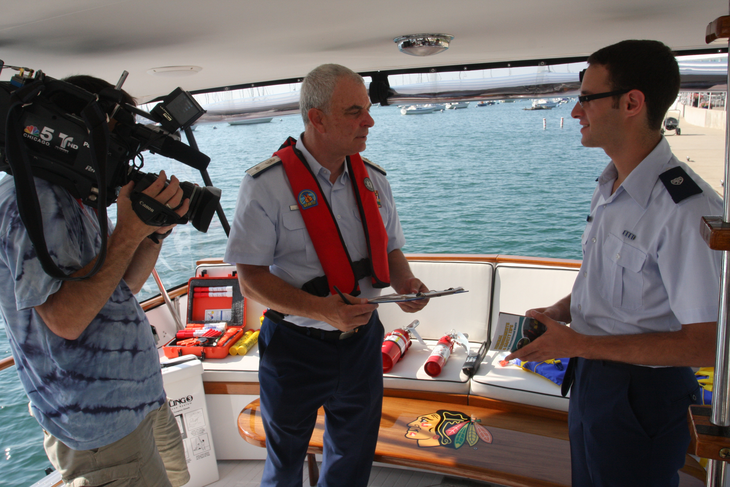  Roth talks with past District 9WR Commodore Randy Podolsky and a news cameraman on the yacht "Blackhawk" at Monroe Harbor in Chicago, July 19, 2013. Earlier, Commodore Podolsky emphasized the Auxiliary's boating safety mission on live television. Ro