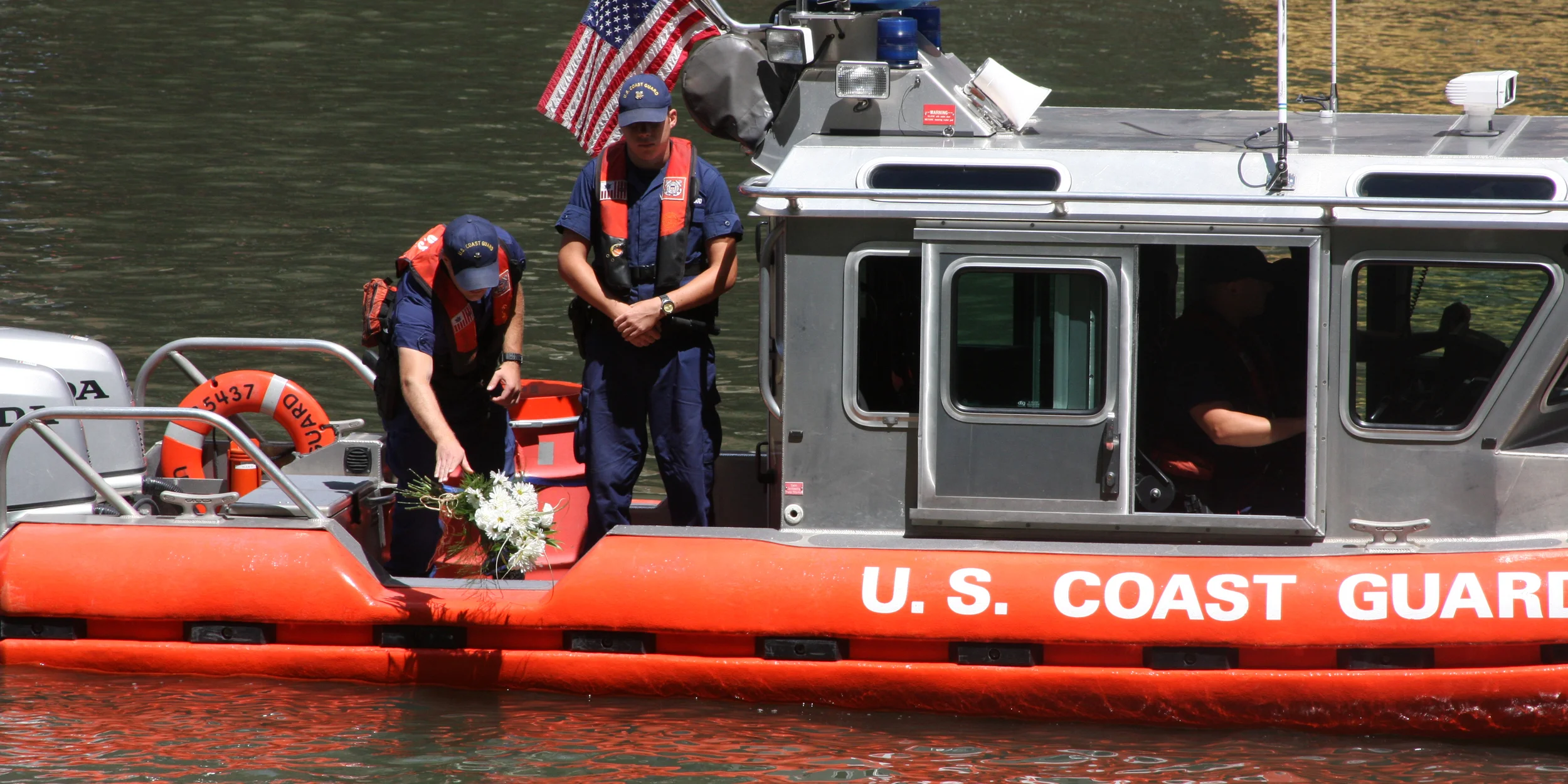 Petty Officer 3rd Class Brennen Coles (left) and Seaman Nicholas Konopka place a bouquet of flowers in the Chicago River in remembrance of the 98th anniversary of the SS Eastland disaster, July 24, 2013. The SS Eastland capsized on the Chicago River in 1915 with more than 2,500 passengers on board. 844 people perished in one of the United States' worst maritime disasters. U.S. Coast Guard photo by auxiliarist Jonathan Roth.