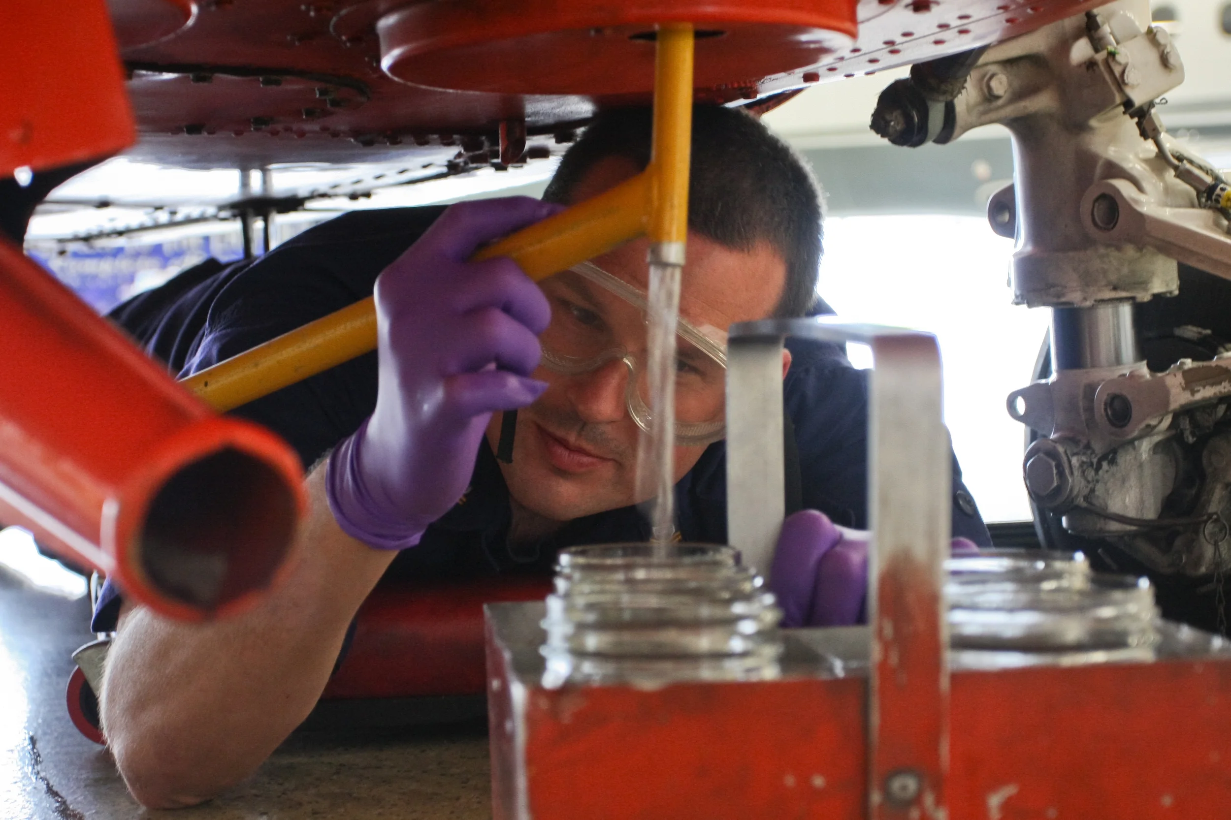Petty Officer 2nd Class Dana Cunningham, from Air Station Traverse City, Mich., takes a fuel sample from an MH-65C Dolphin helicopter at Air Facility Waukegan, Ill., July 31, 2013. Fuel samples are taken every morning to ensure that the fuel is free of water and debris. U.S. Coast Guard photo by auxiliarist Jonathan Roth.