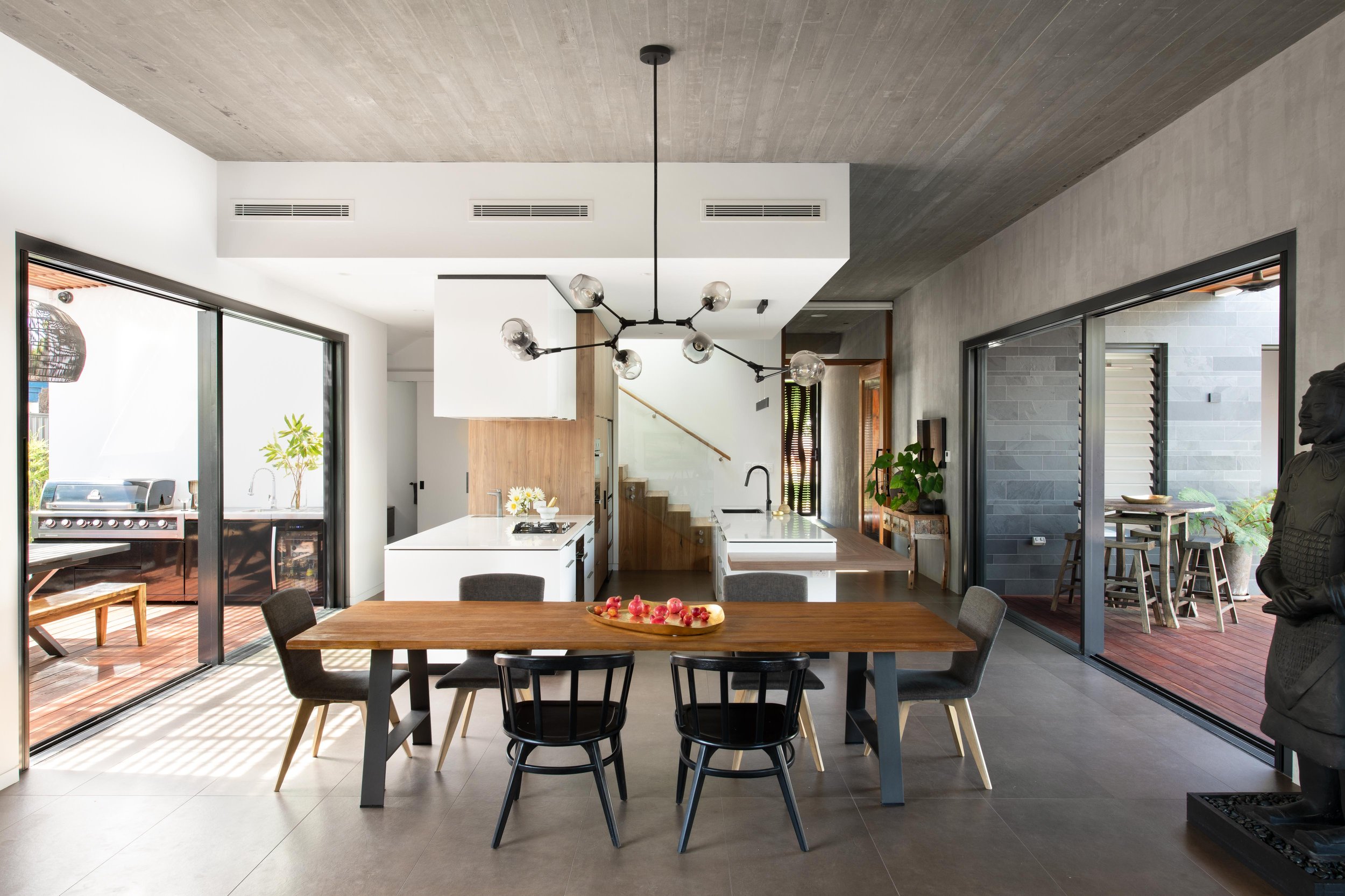 An open-plan dining and kitchen with courtyards on both sides at Arklen's custom build in Ardross, Perth WA.