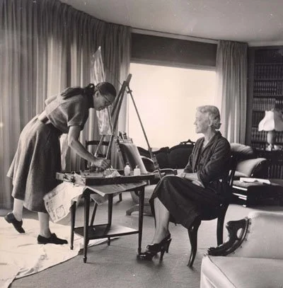 Senator Smith sitting in her living room as Emily Muir paints her portrait.