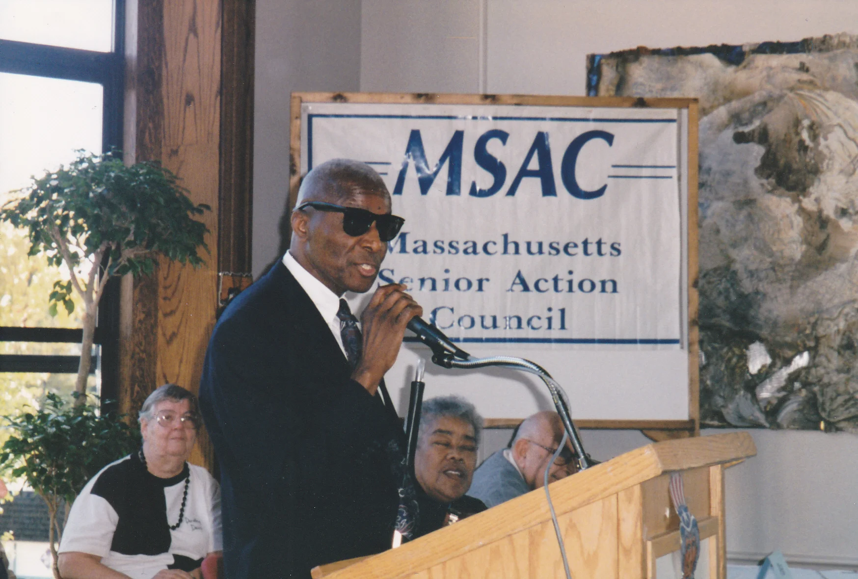 Man on a podium with an MSAC banner in the background