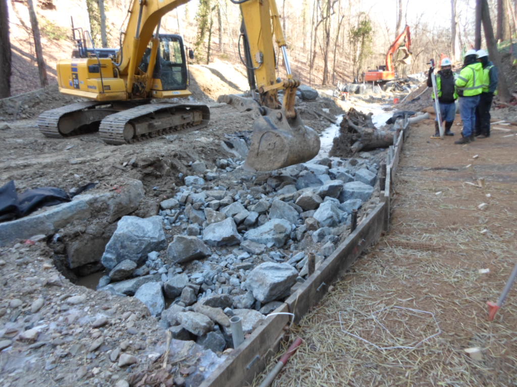 The contractor sets a specified mix of stones and river rocks in the riffle grade control.