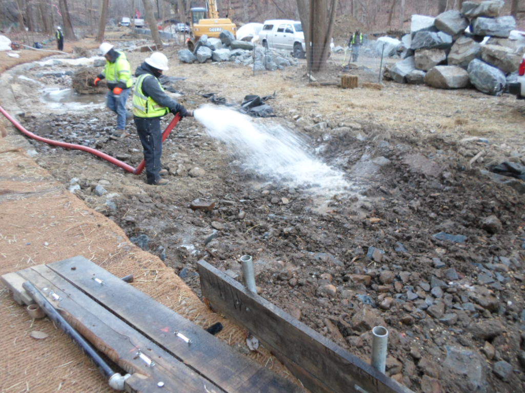 Smaller rocks and pebbles are washed into the gaps in the large stones to finish the riffle grade control.