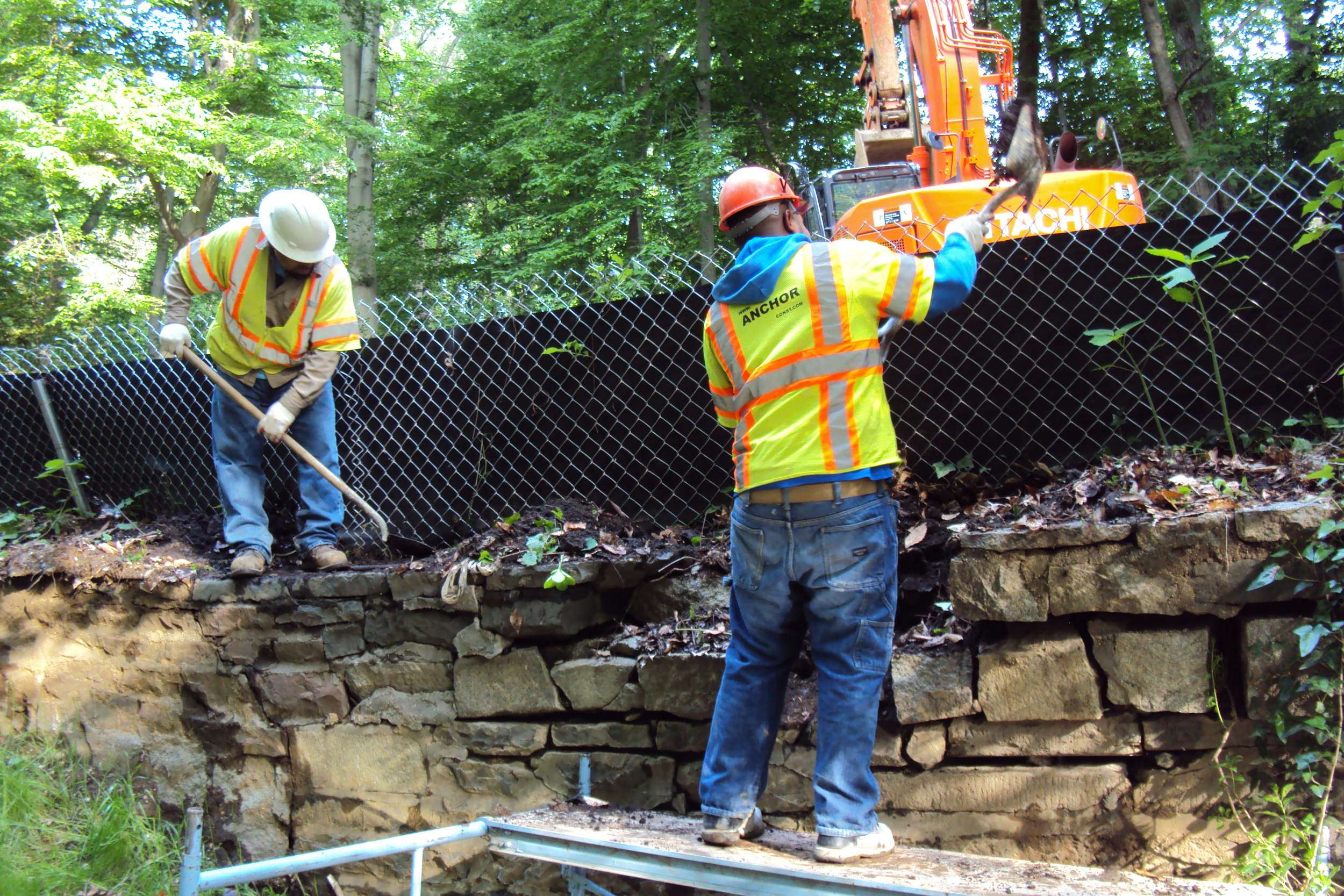 The crew resets the original stone headwall and applies fresh mortar at the joints