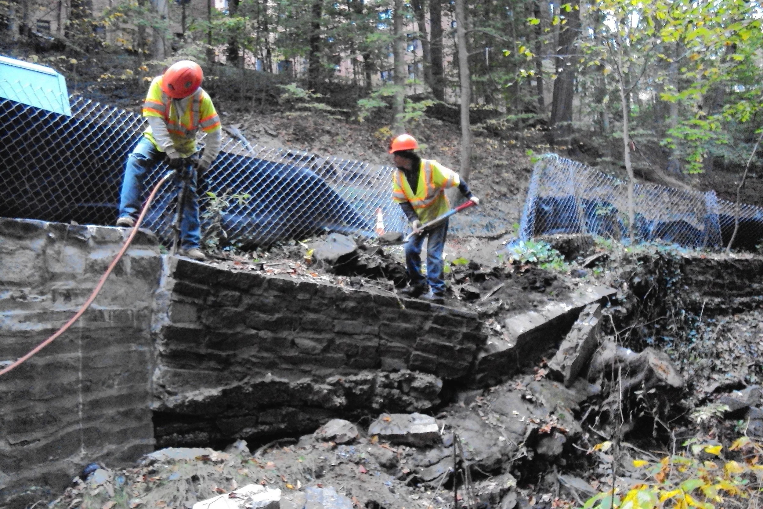 Removal of existing damaged retaining wall. Existing stone to be salvaged and used on the project.