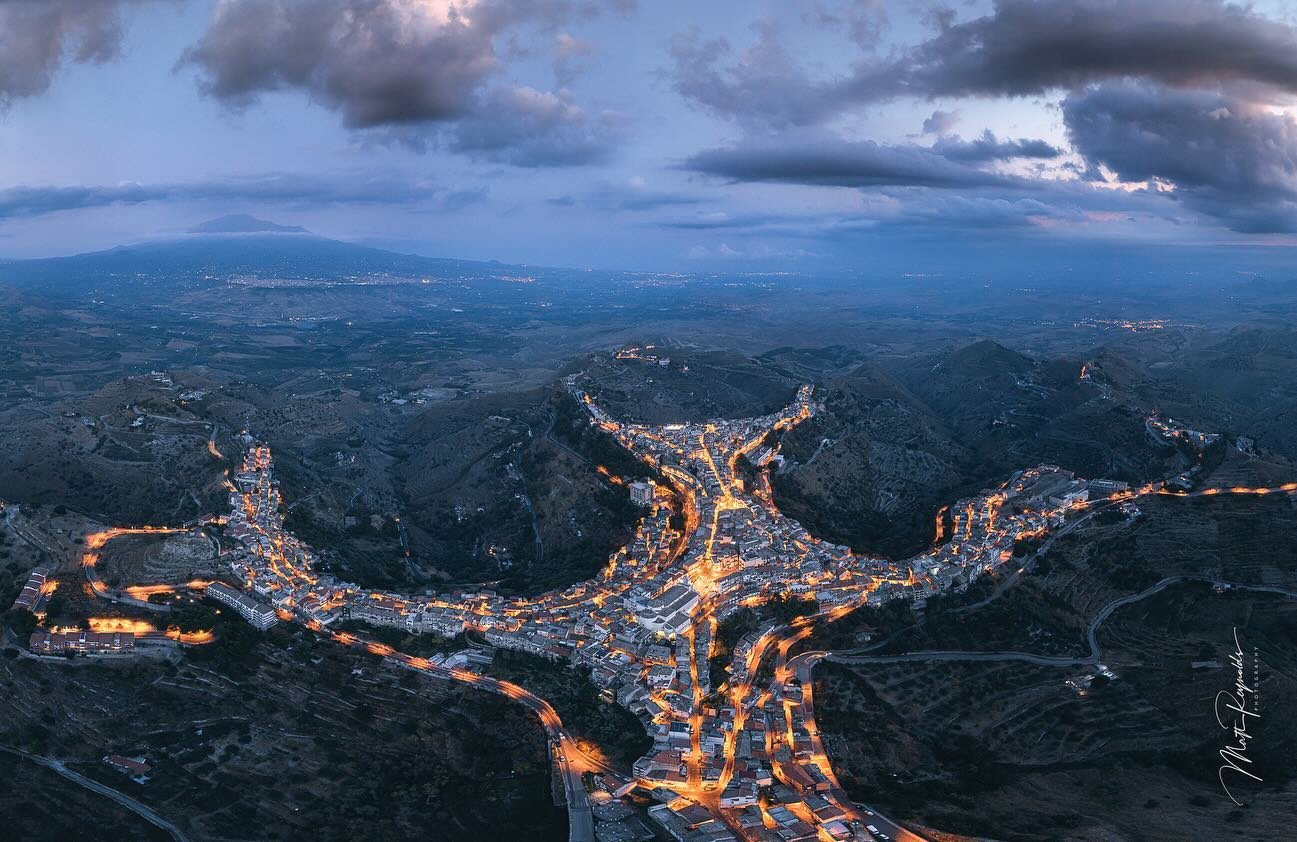 One of the most interesting photos I have ever taken. &ldquo;Minotaur&rdquo;. Looks like CGI but is an actual photo of a cliff top town in Sicily after sunset when the town lights came on.  Mt Etna is on the left. Provided a 2nd image ; can zoom in t