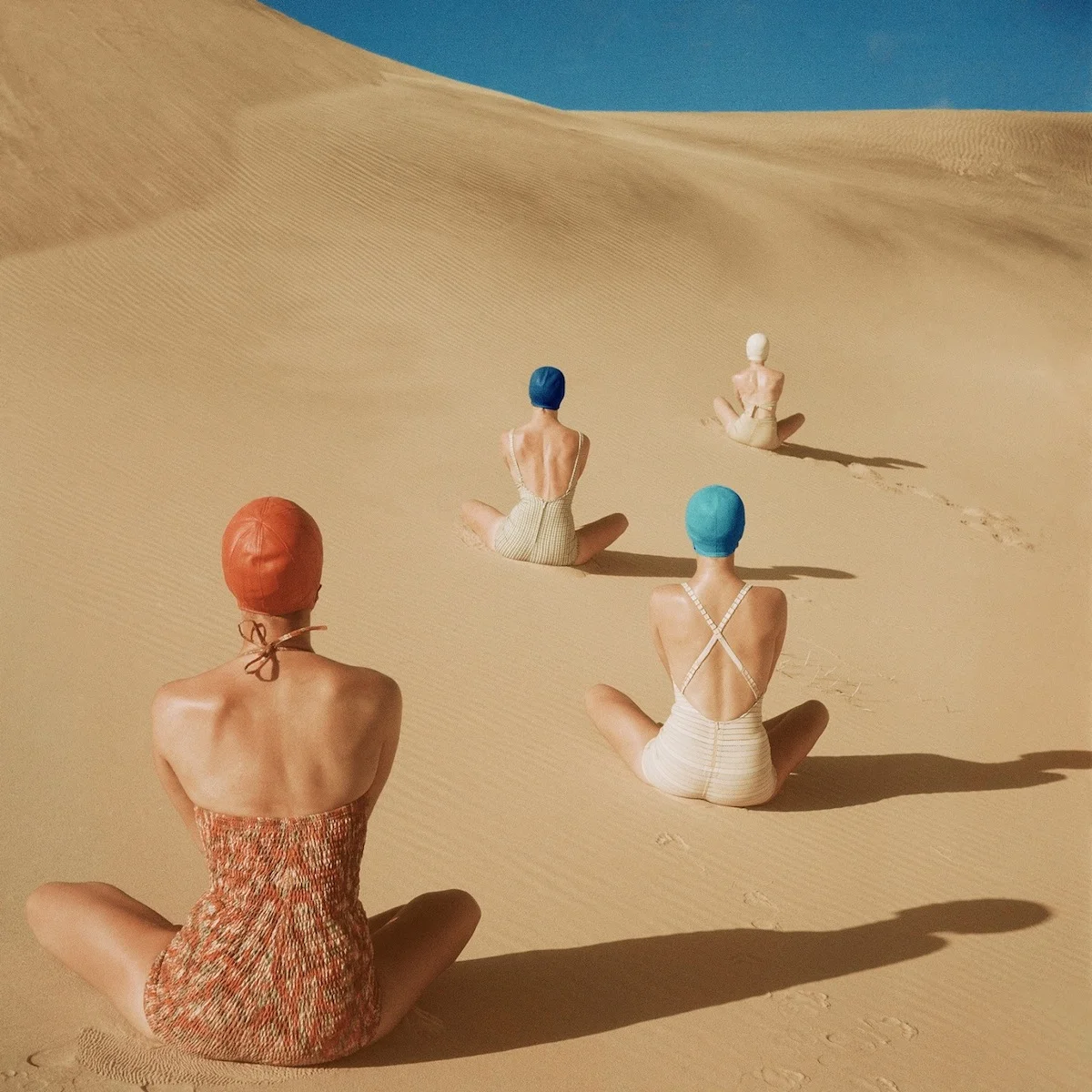 Duplicate of four back-views of seated models in swimsuits by Cole of California, Mabs, Caltex amd Catalina, and bathing caps