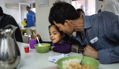 Rahmad and his daughter Rayhon eat lunch in the soup kitchen of Caritas Athens Refugee Centre, Greece. Photo: Andrew McConnell/CRS