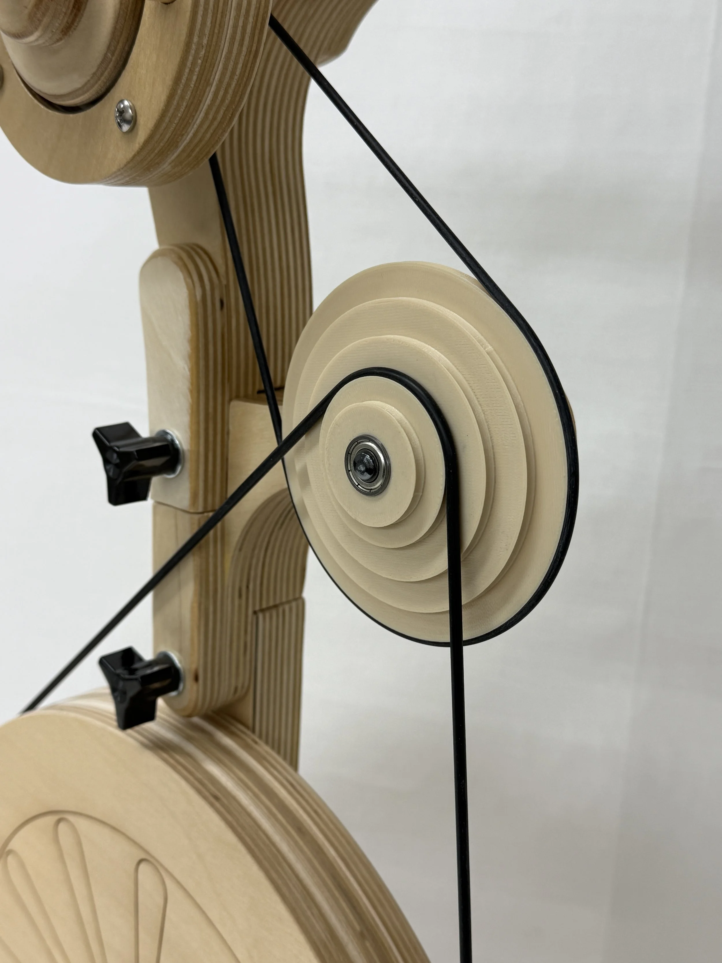 Close-up view of a wooden mechanical contraption with black belts and knobs.