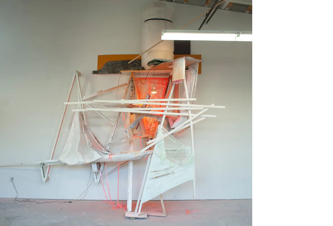 UNDER CONSTRUCTION NO. 1 site specific installation with wood, cellophane, aluminum, acrylic paint, spray enamel, cardboard, light bulbs, fan, extension cords, clear polyethylene sheeting, vinyl siding, flagging tape, and bubble wrap, 178 x 196 x 62 inches, 2013