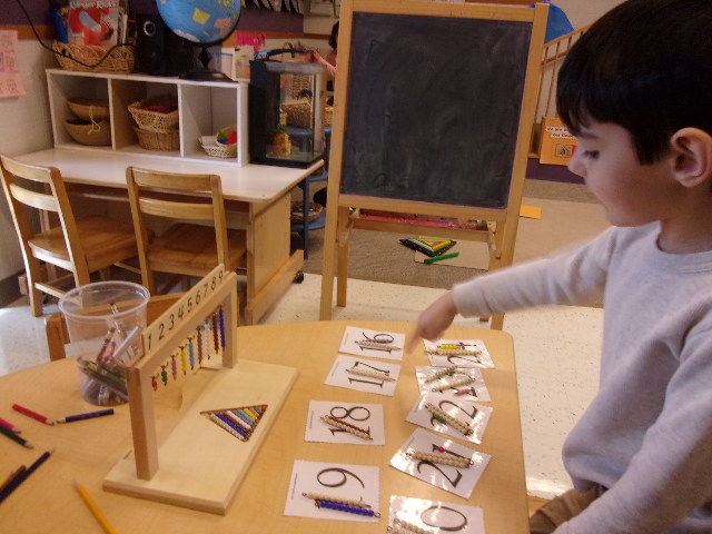 Aaron matching bead bars to numbers on the bead bar row and number cards.