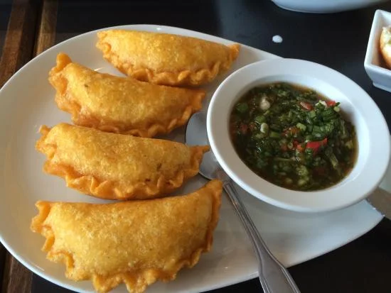 Empanada - Known as the “King of street food” in Colombia, these empanadas are our personal favorite in all of South America. Of course there are many filling options, but our personal favorite is filled with minced meat, egg, cheese, and vegetables, and served with a mouthwatering chili salsa (also pictured).