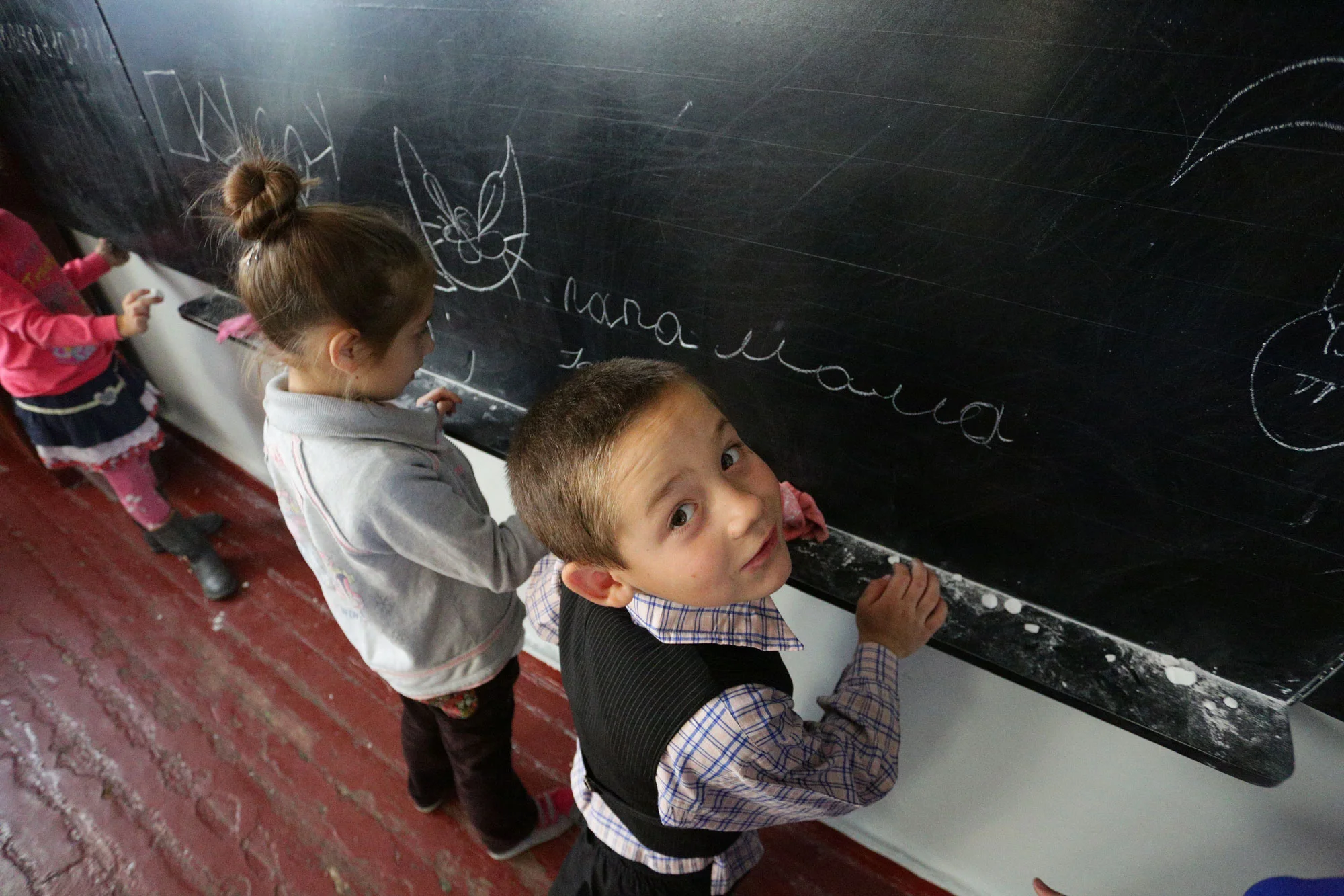 Des enfants écrivent au tableau dans une école du village de Staromykhailovka, sur la ligne de front, entre les villes de Donetsk et Mariyanovka, en Ukraine. © UNICEF / Aleksey Filippov