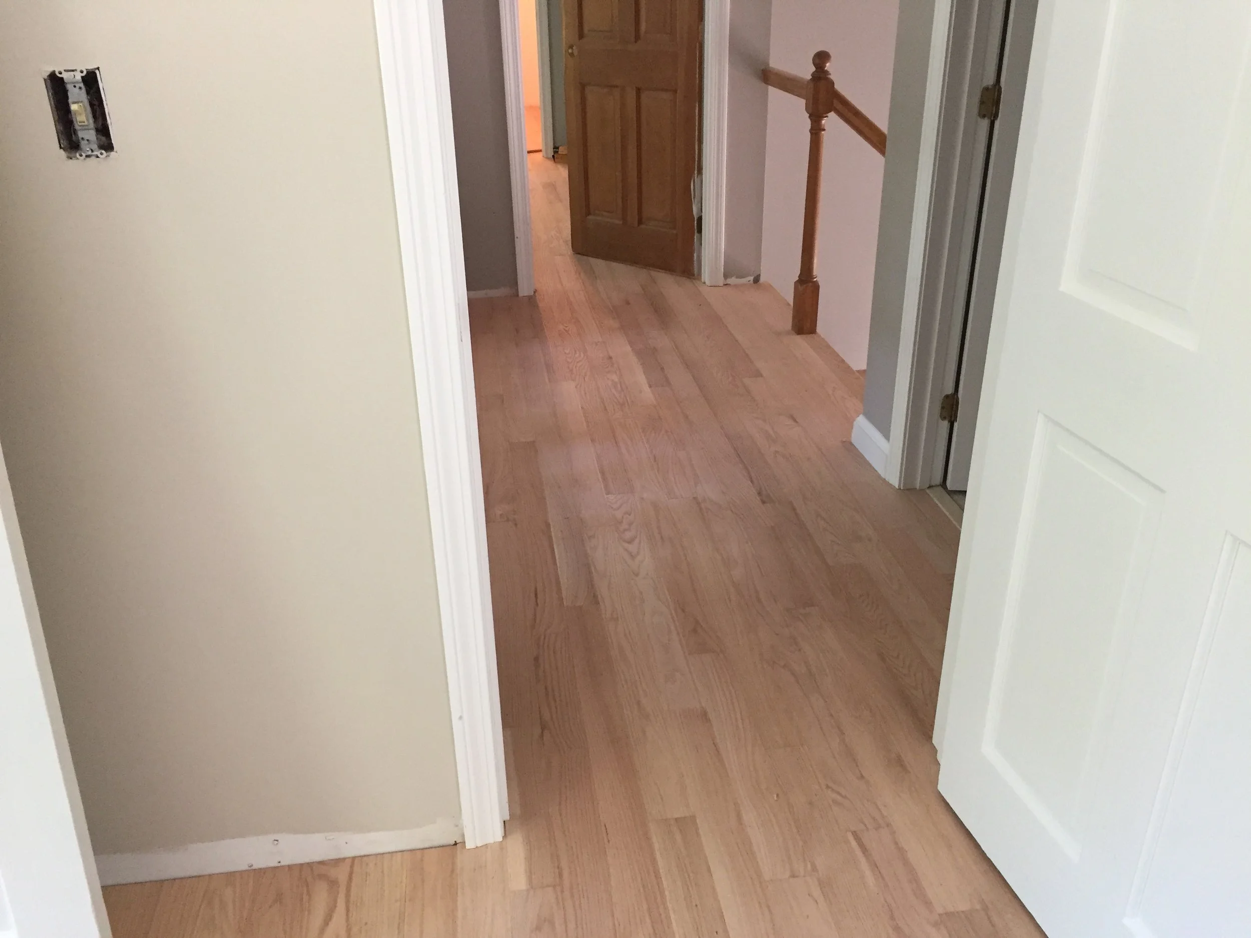AFTER - hall with new red oak flooring installed (unstained)