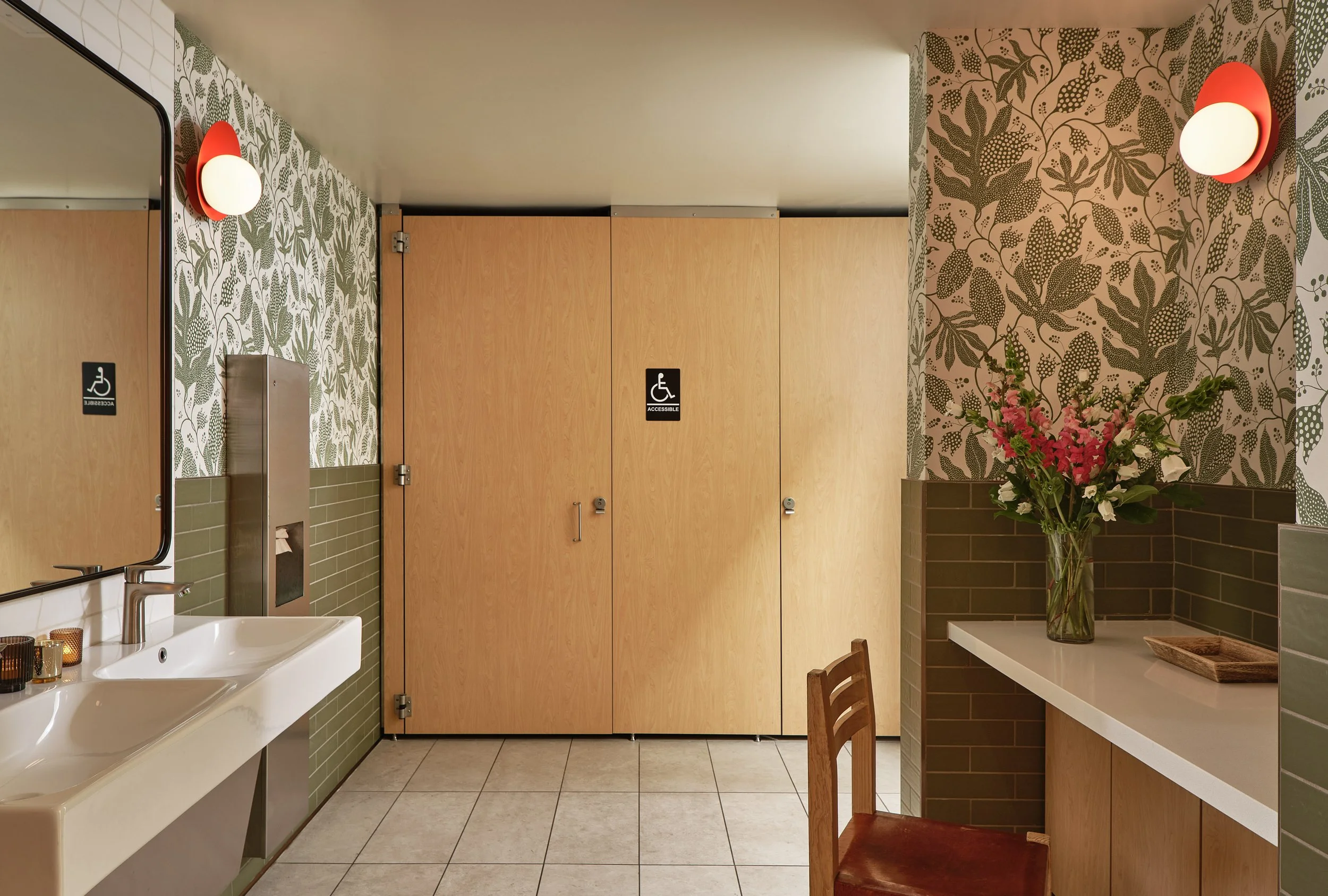 Farming Hope all-gender restroom remodel in San Francisco with accessible stalls, green tile, botanical wallpaper, and custom cabinetry.